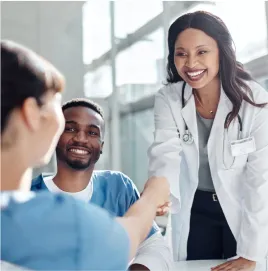 Médecin femme souriante tendant la main pour recevoir quelque chose d'un collègue