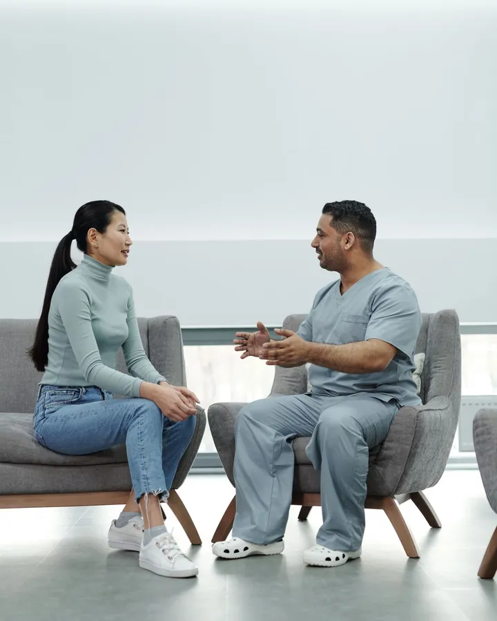 Doctor in scrubs talking with a patient in a modern clinic lounge